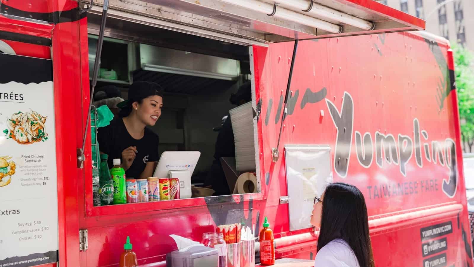 a person standing behind a red food truck