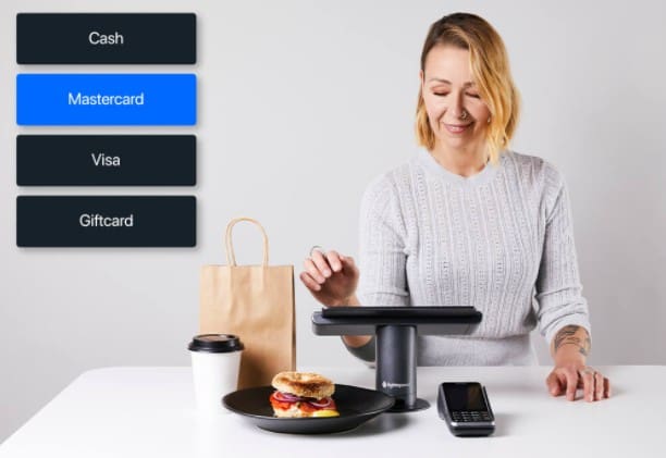 a person sitting at a tablet with a credit card reader