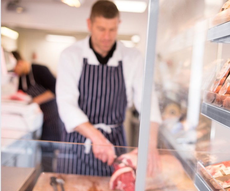 an out of focus photo of a butcher slicing meat inside of a butcher shop